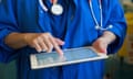 A doctor on a ward checks a patients' records on an Ipad