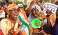 Women waving Niger flags, blowing horns and holding placards.