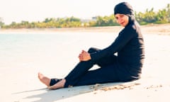 young woman wearing burkini sitting by the beach in dubai