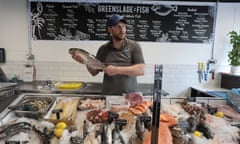Tim Greenslade holds up a fish in his fishmonger’s shop in Poole, Dorset