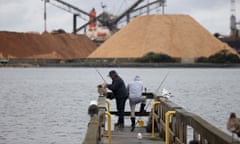 Fishers on Burnie jetty are dwarfed by mountains of woodchip ready for loading at the port in the Tasmanian seat of Braddon