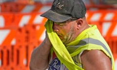 A construction worker wipes away sweat on his shirt.