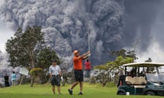 Hawaii's Kilauea Volcano Erupts Forcing Evacuations<br>People play golf as an ash plume rises in the distance from the Kilauea volcano on Hawaii's Big Island on May 15, 2018 in Hawaii Volcanoes National Park, Hawaii.
