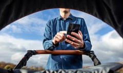 Man uses smartphone while pushing a baby’s pram