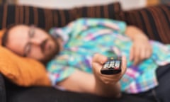 Man relaxing in sofa with remote control watching TV.