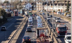 Traffic drives along a multi-lane carriageway in London with houses next to it