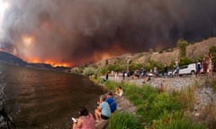 FILES-CANADA-FIRE<br>(FILES) Residents watch the McDougall Creek wildfire in West Kelowna, British Columbia, Canada, on August 17, 2023, from Kelowna. Ottawa estimates the annual cost of fighting wildfires at Can$1 billion, and noted that, according to the Canadian Climate Institute, climate impacts such as more and bigger fires could halve Canada's projected economic growth in the coming years. Most worrying, he said, is that Canadians aren't dealing anymore with one localized disaster every few years or decades, but rather "several events stacked on top of each other in a single year" -- including fires, floods, heatwaves and powerful storms. (Photo by Darren HULL / AFP) (Photo by DARREN HULL/AFP via Getty Images)