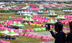 Rows of tents arranged for the jamboree, with a resident in the foreground taken a picture on his phone
