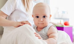 Newborn baby sitting by mother's knees