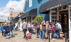 people shopping on a sunny day and queuing to enter Burberry