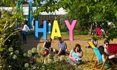 People relaxing on lawn in late afternoon summer sunshine in garden area at Hay Festival