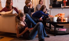 Family of five watching television together in living  room.