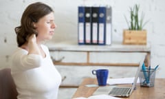 Young stressed businesswoman sitting in front of laptop and holding her neck with pained expression.