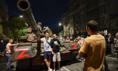 Servicemen of the Wagner Group military company sit atop of a tank, as local civilians pose for a photo