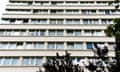 Close-up of a 60s or 70s high-rise block, looking up the side of the building , with branches of a tree visible in the bottom of the picture