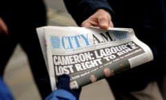 A newspaper seller hands out a copy of City AM in London