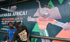 People sit at a bus stop decorated with the Africa Cup of Nations official mascot Awkwaba in Abidjan, Ivory Coast, which is hosting the tournament.