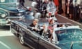 John F Kennedy and Jacqueline Kennedy riding in car.