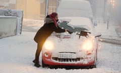 A woman clears snow from her car