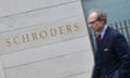 A man walks past a Schroders sign