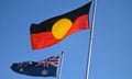 An Aboriginal flag is seen next to the Australian flag against a blue sky