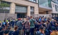 Photographers and security officials stand outside a modern building