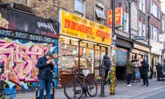 The Beigel Shop signn with man outside eating what appears to be a bagel