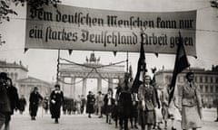 A column of people, led by two women carrying Nazi flags, and others  a huge banner saying 'Dem Deutschen Menschen kann nur