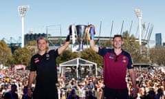 Collingwood’s Darcy Moore and Brisbane’s Harris Andrews hold the premiership cup in front of a big crowd outside the MCG