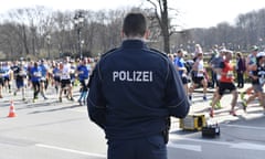 A German police officer stands guard over runners participating in the Berlin half-marathon.
