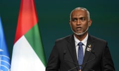 Mohamed Muizzu speaking at a podium in a suit and tie