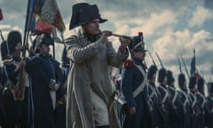 Joaquin Phoenix as Napoleon holding a telescope at the head of a line of troops