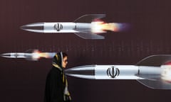 Woman walks past poster depicting missiles in flight