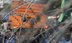 Protesters hold up a sign behind razor wire