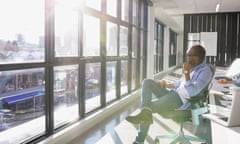 Pensive businessman looking out sunny office window