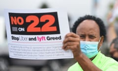 A driver holds up a sign supporting a no vote on Prop 22 in Oakland, California last year.