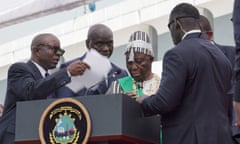 Joseph Boakai is helped away from the podium during the inauguration ceremony in Monrovia