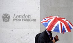 A worker shelters from the rain under a Union Flag umbrella as he passes the London Stock Exchange