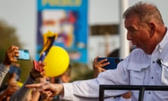 A man wearing a white button-down looks at a crowd and points