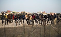 Would-be immigrants sit atop a border fence separating Morocco from the north African Spanish enclave of Melilla