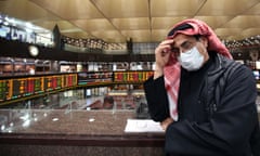 A Kuwaiti trader wearing a protective mask follows the market at the Boursa Kuwait stock exchange in Kuwait City