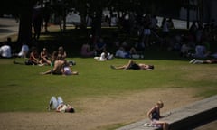 People sit and lie in the sun and shade near City Hall in London