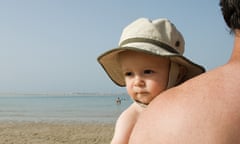 A father holds his son at a beach