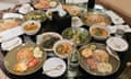 Plates of food fill a round wooden table