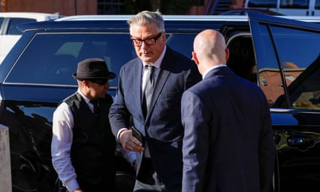 a man in suit, tie and glasses exits a large black vehicle