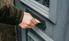 Woman posting a letter through a letterbox