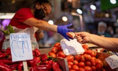 A customer pays for vegetables at the Maravillas market in Madrid