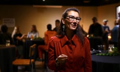 A woman in a red dress, wearing glasses, speaking to someone off camera