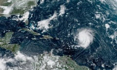 A satellite image of a white spiral cloud on the right over blue water approaching a green archipelago to the left, between two green land masses (North America and South America).