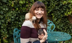 Donna, grinning, sitting at a garden table with a rat on her shoulder and another in her hands